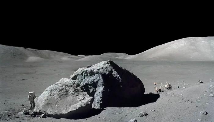Image shows astronaut-geologist standing next to a huge lunar boulder
